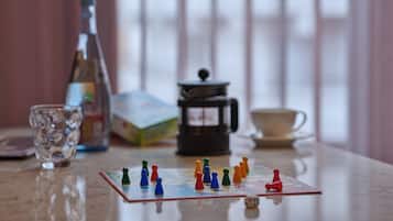 A board game set on a table with a coffee maker and a glass in the background.