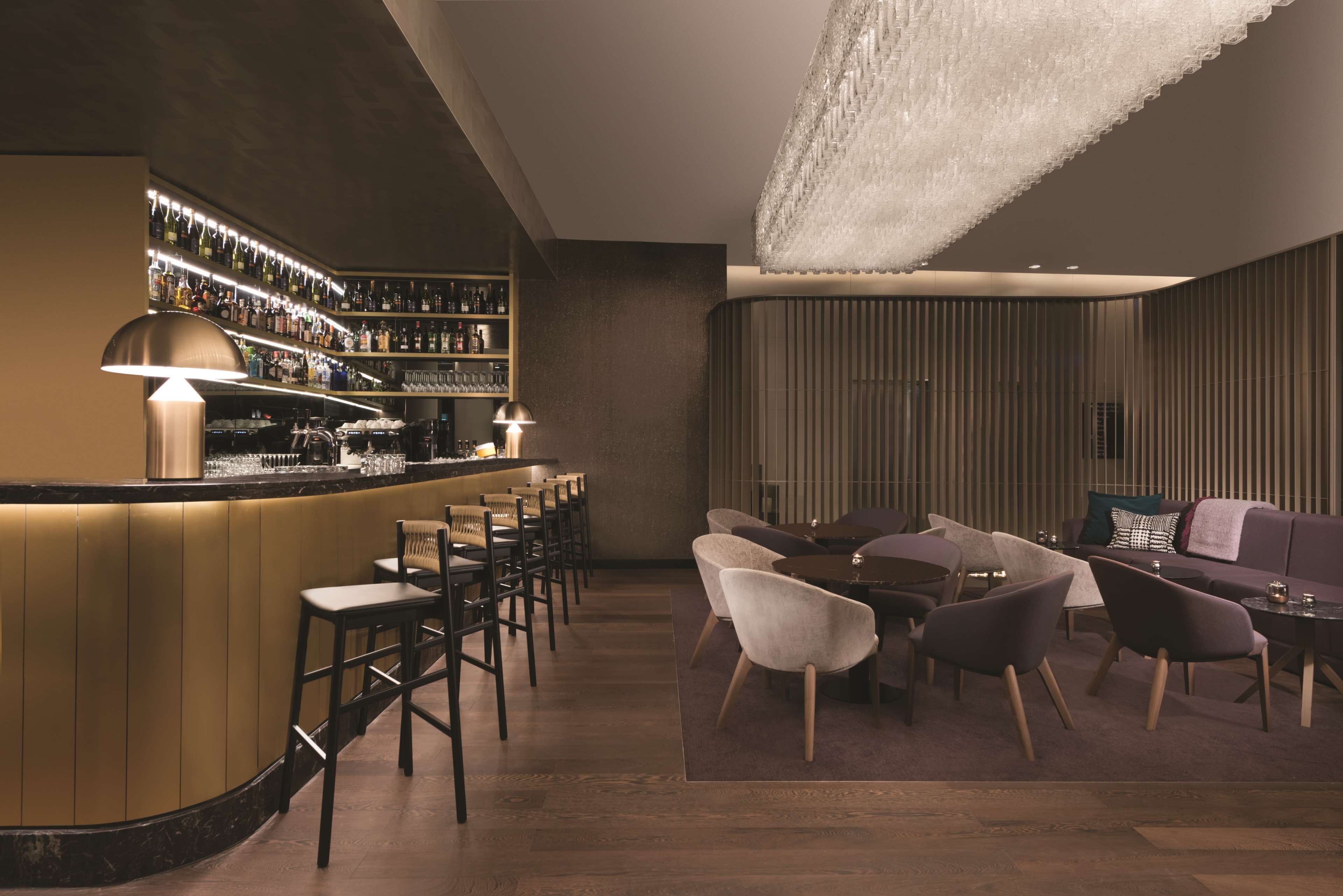 A bar area with a curved counter, multiple bar stools, and a wine rack.