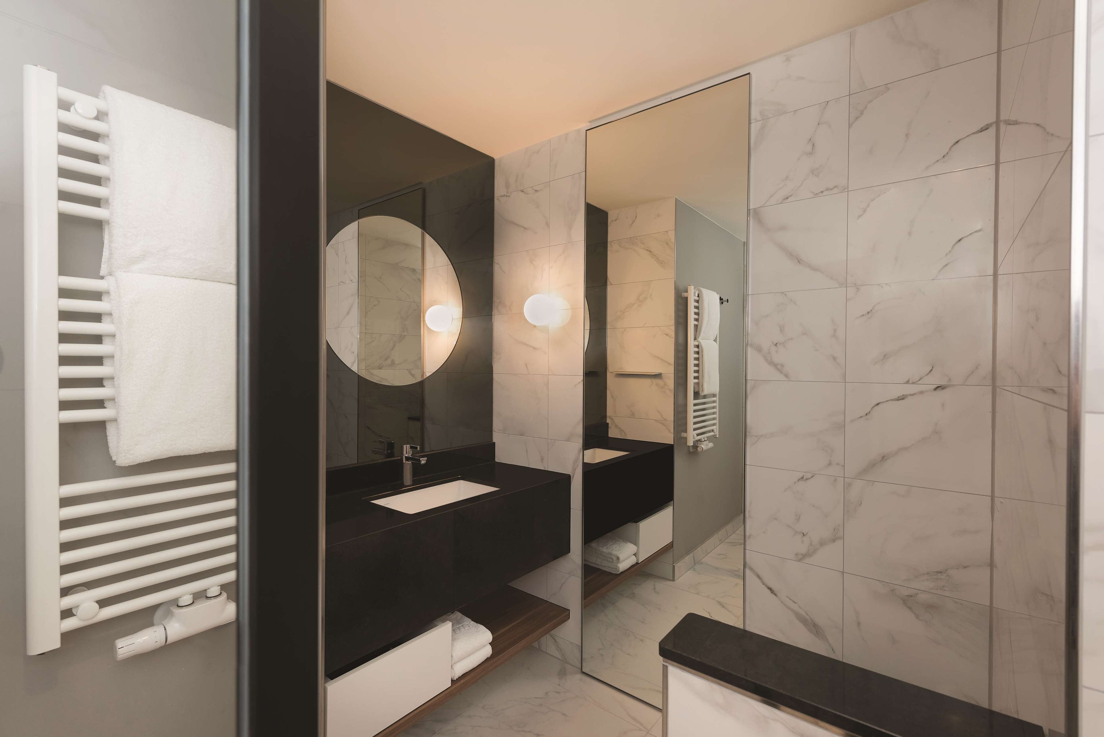 A modern bathroom with a black sink, white towel rack, and a large mirror.