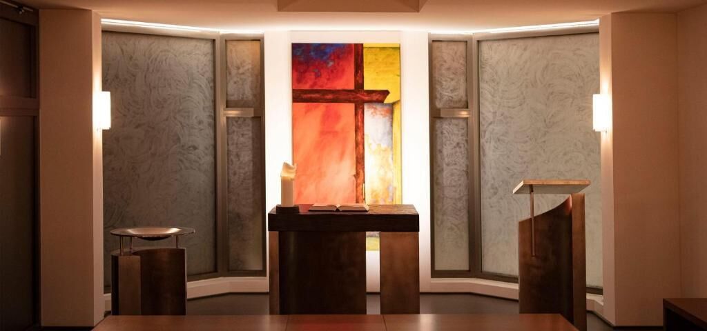 Een moderne badkamer met een centraal geplaatst wastafel, een spiegel en een kleurrijk abstract schilderij aan de muur.