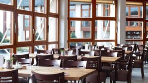 Un comedor amplio con ventanas grandes, mesas y sillas de madera.