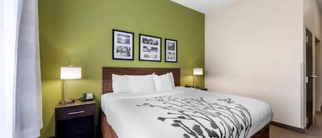 Une chambre d’hôtel avec un grand lit, des murs verts et trois tableaux encadrés accrochés au mur.