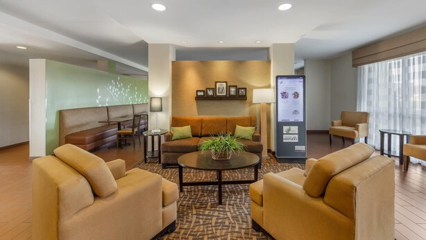 Un hall d’hôtel avec un canapé, des fauteuils, une table basse et un comptoir de réception.