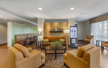 A hotel lobby with a sofa, armchairs, a coffee table, and a reception desk.