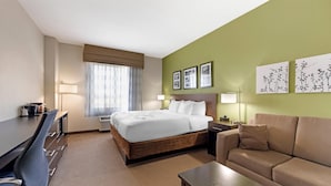 Une chambre d’hôtel avec un lit, un bureau, un canapé et une fenêtre avec des rideaux.