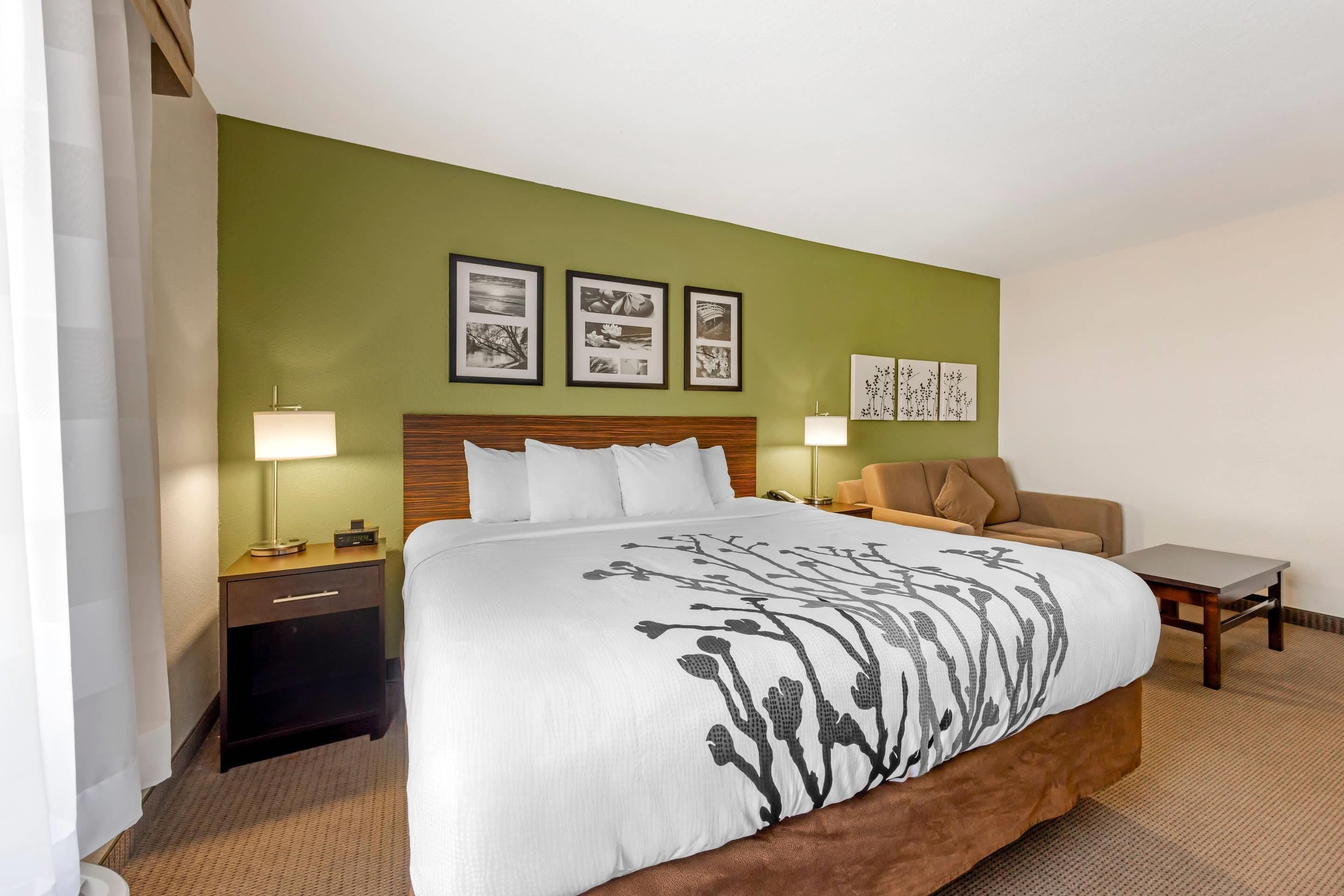 A hotel room with a large bed, two bedside tables, a nightstand, a chair, and a small table.
