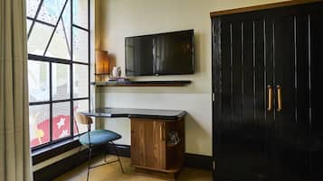 Una habitación con escritorio, silla, televisor y armario.