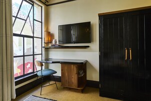 Una habitación con escritorio, silla, televisor y armario.
