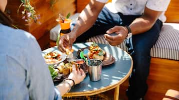 Una mesa redonda con diversos platos y bebidas, rodeada de gente sentada en un sofá.