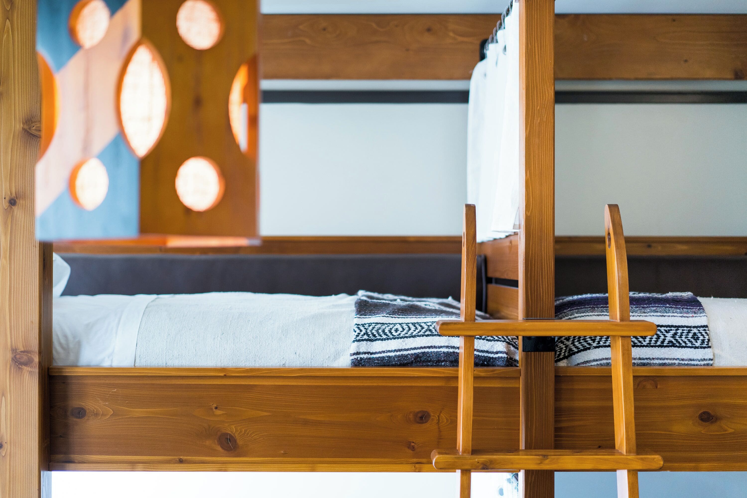 A wooden bunk bed with a headboard that has circular cutouts.