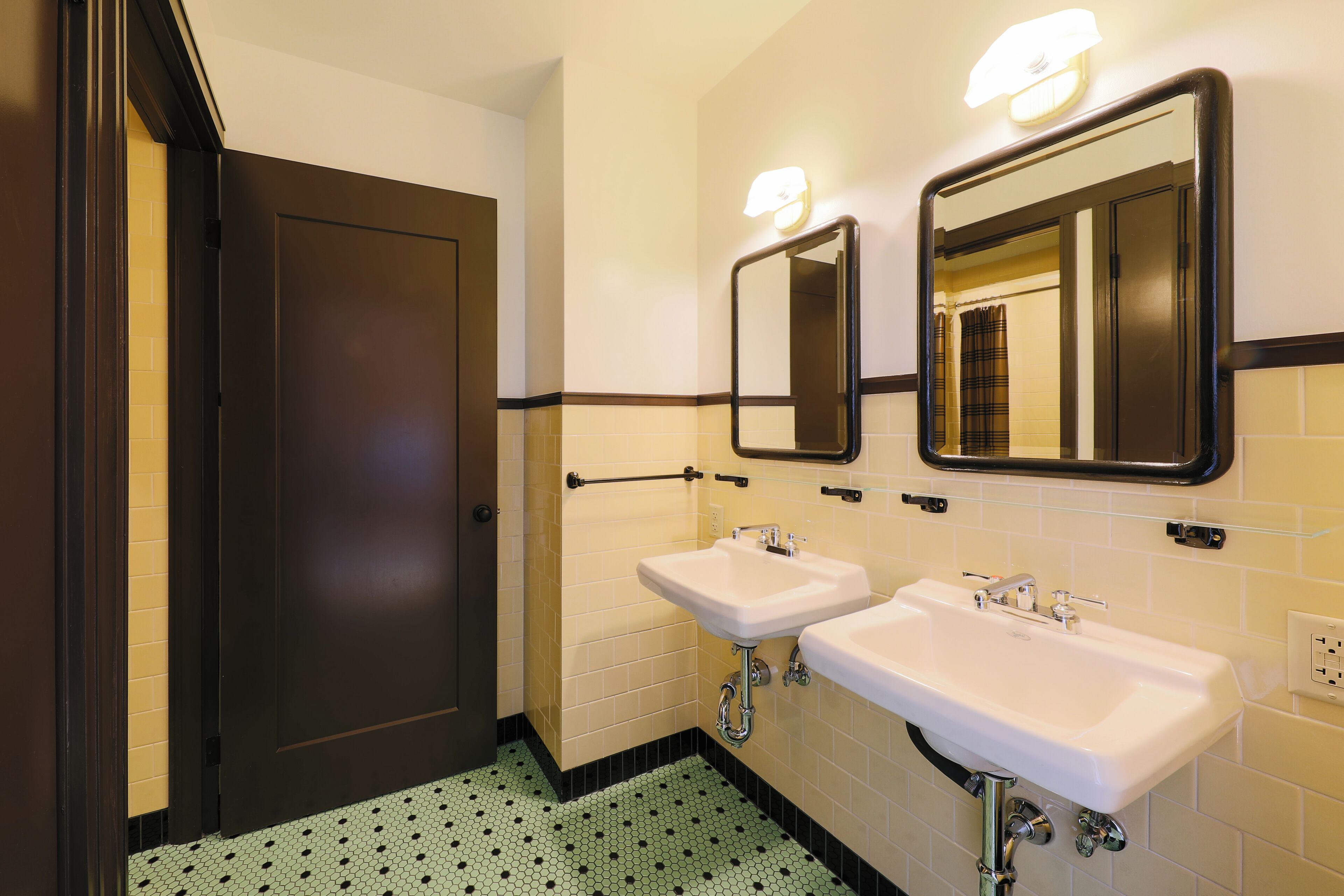 A bathroom with two sinks, a mirror, and a door.