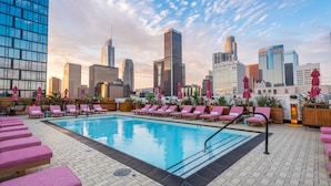 A rooftop pool with pink lounge chairs and umbrellas, surrounded by city buildings. - Freehand Los Angeles (Los Angeles)