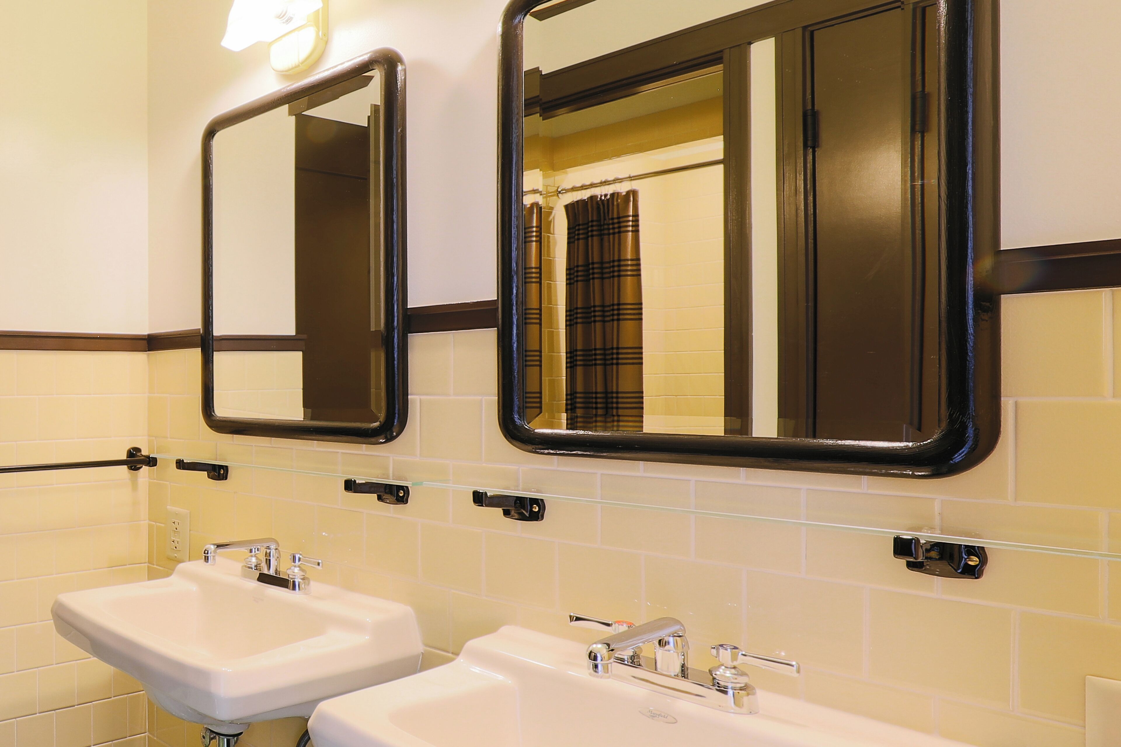 Un bagno con due lavandini, specchi e portasciugamani.