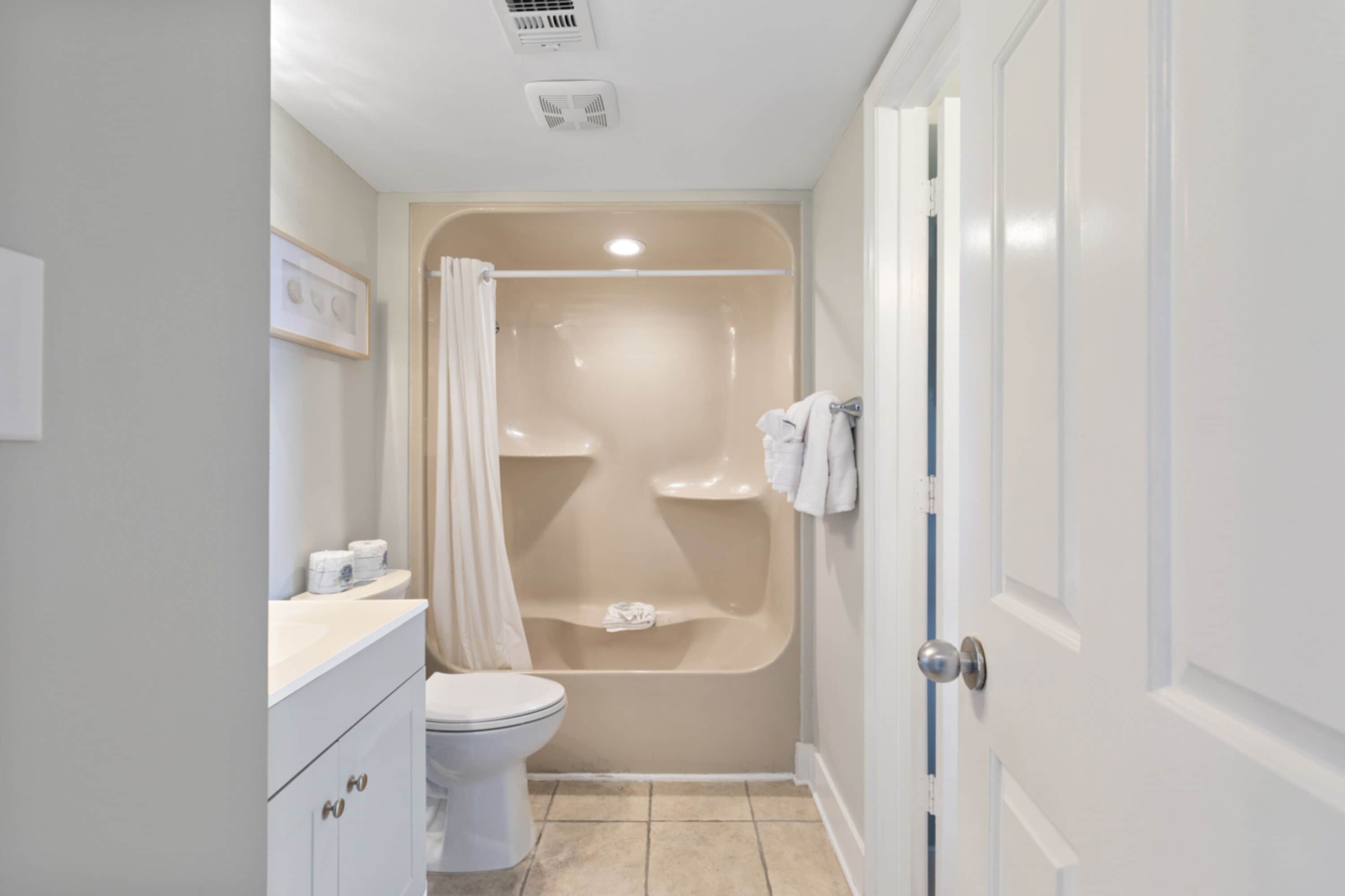 A bathroom with a bathtub, toilet, and vanity.