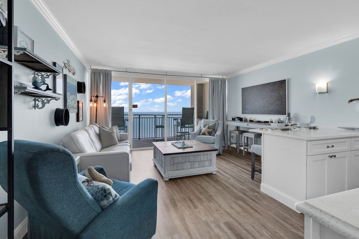 A modern living room with a sofa, coffee table, and a dining area with a kitchen counter.