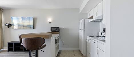 A modern kitchen with white cabinets, a wooden countertop, and a built-in microwave.