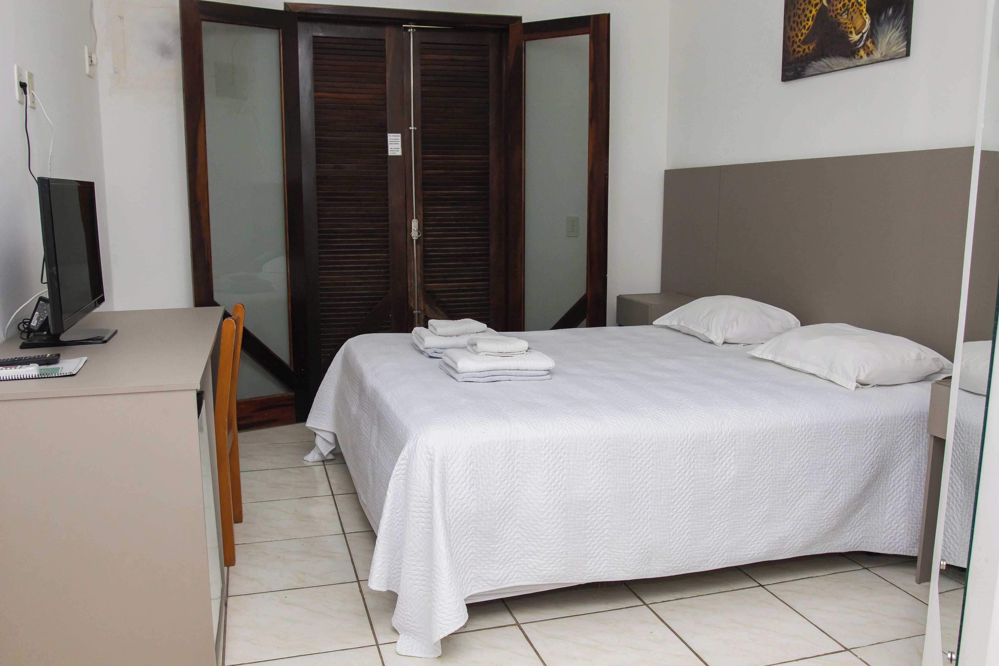 Quarto com cama, escrivaninha, cadeira e guarda-roupa.