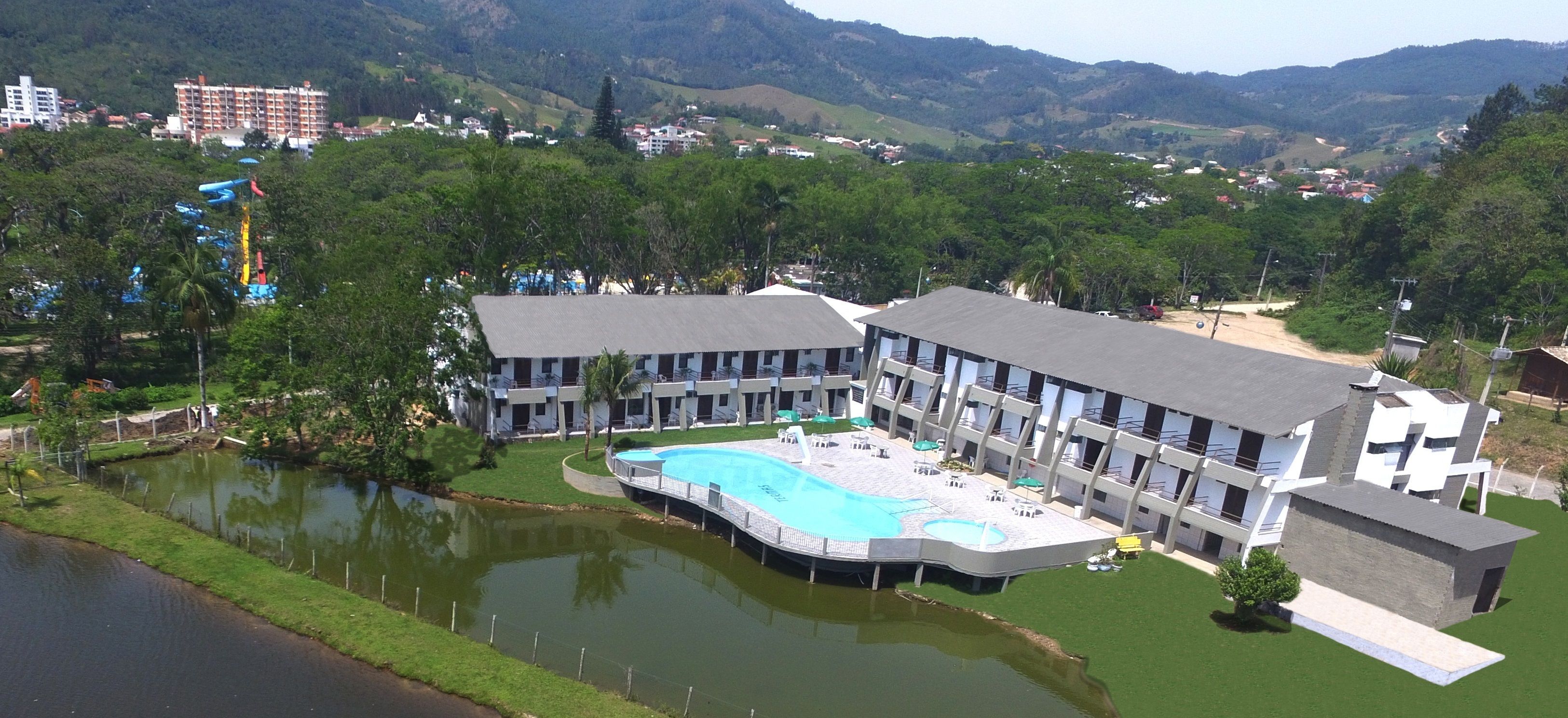 Un hotel con piscina, un pequeño estanque y vistas a las colinas circundantes.