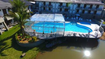 A hotel with a large pool area, including a sunken section and a covered deck.