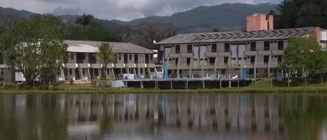 A building with multiple floors and a flat roof, situated next to a calm body of water.