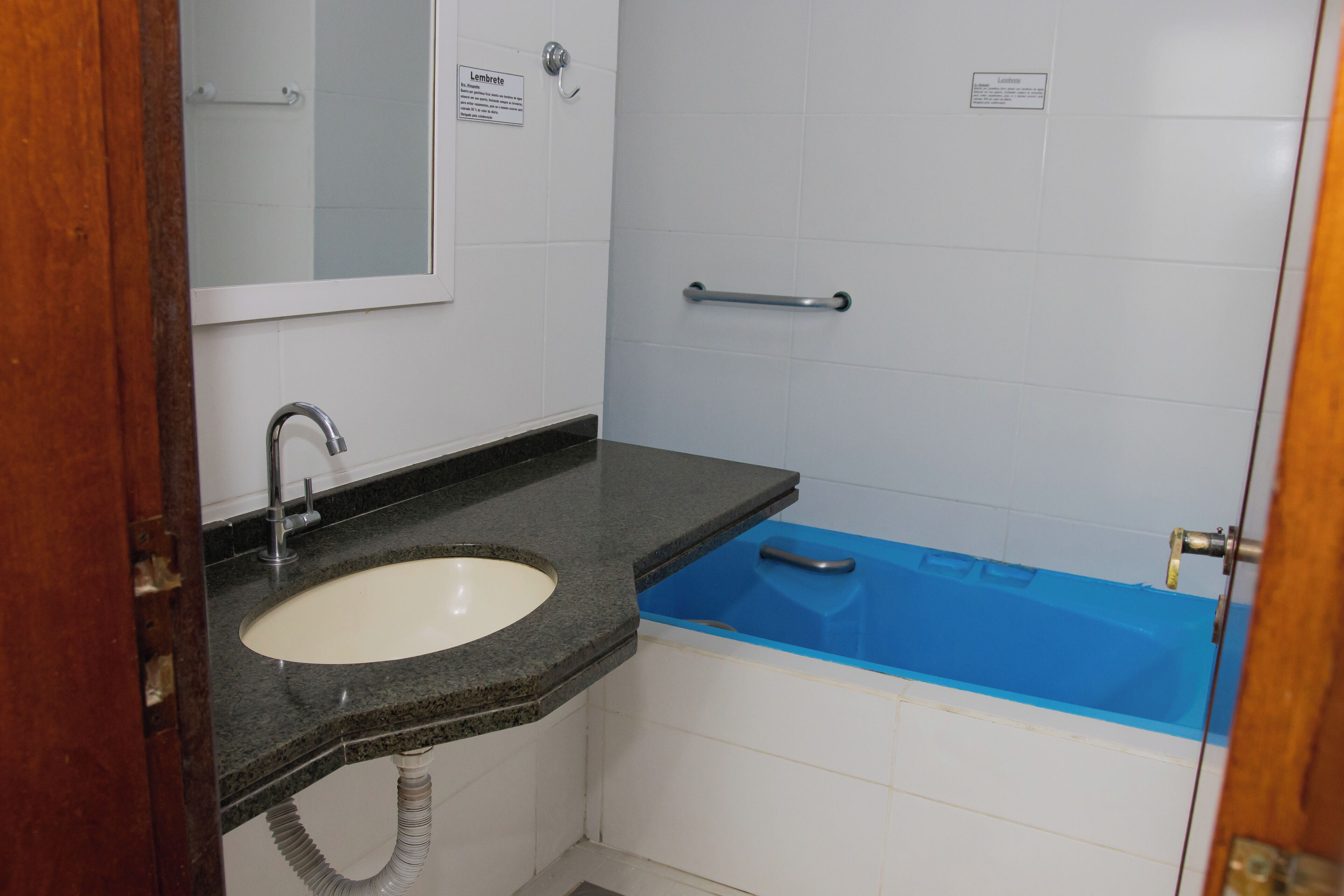 Un baño con lavamanos, espejo y bañera azul.