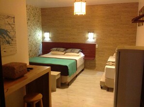A small, cozy room with a bed, a desk, and a chair. There is a wall with a bamboo pattern and a light fixture above the bed. - Pousada A Cabana (Garopaba)