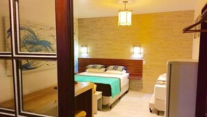 Una habitación de hotel con cama, mesita de noche, silla y un escritorio pequeño con taburete.