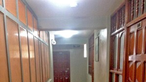 Un pasillo con piso a cuadros, una puerta de madera a la derecha y una puerta roja al final.