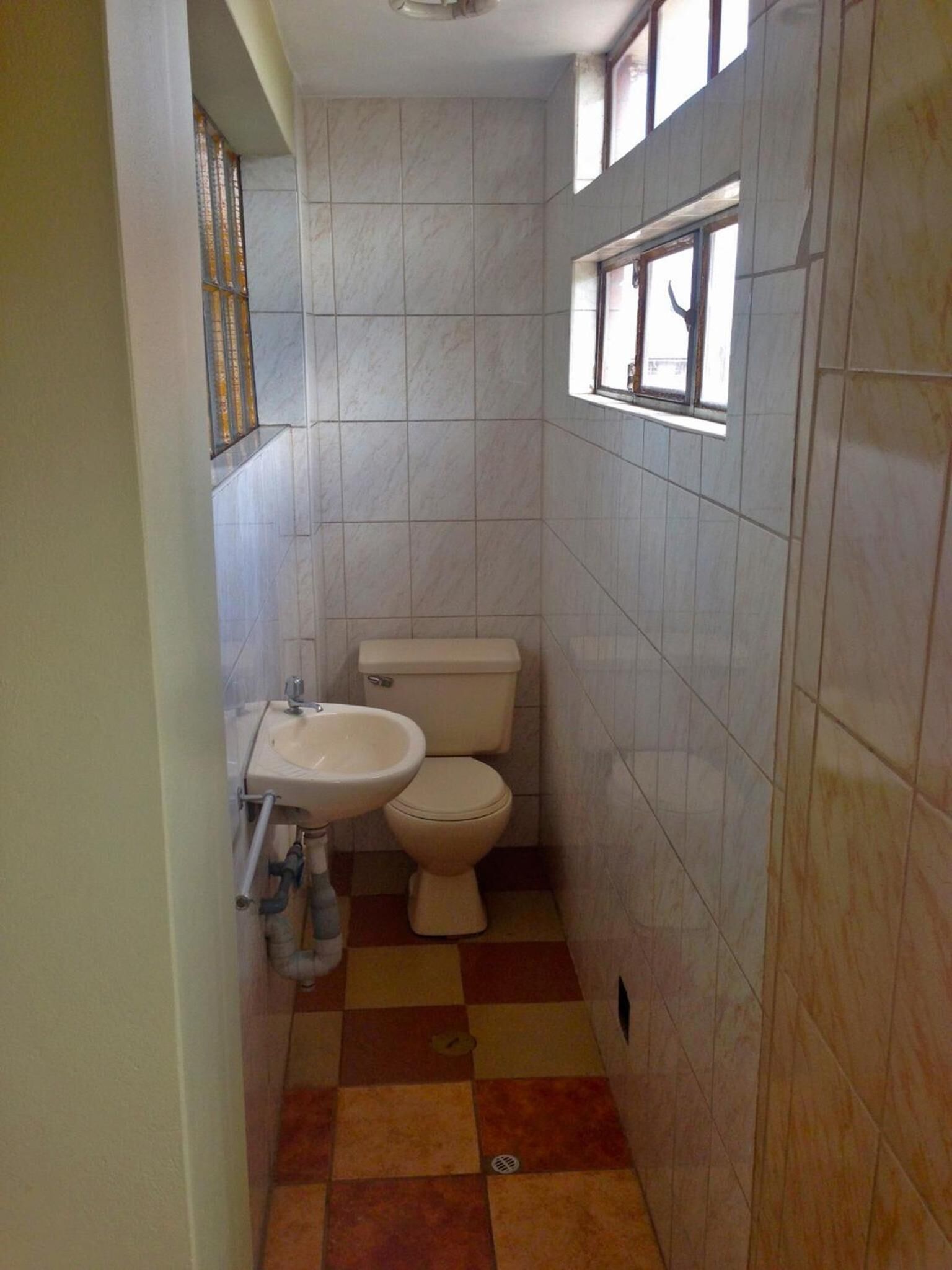 A small bathroom with a toilet, sink, and a window.
