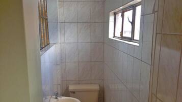A small bathroom with a toilet, sink, and a window.