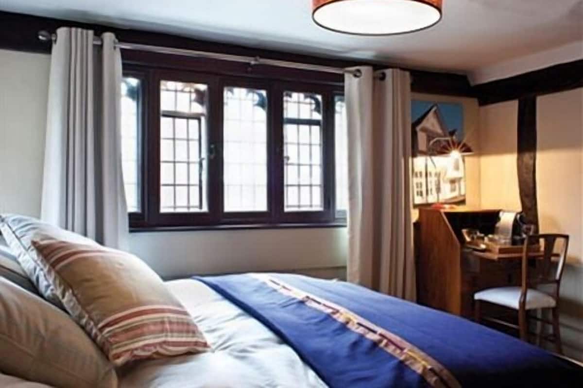 A bedroom with a bed, a desk, and a chair.