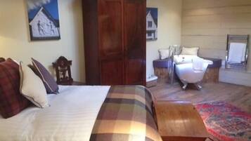 A bedroom with a bed, a wooden wardrobe, a nightstand, a chair, and a large rug.