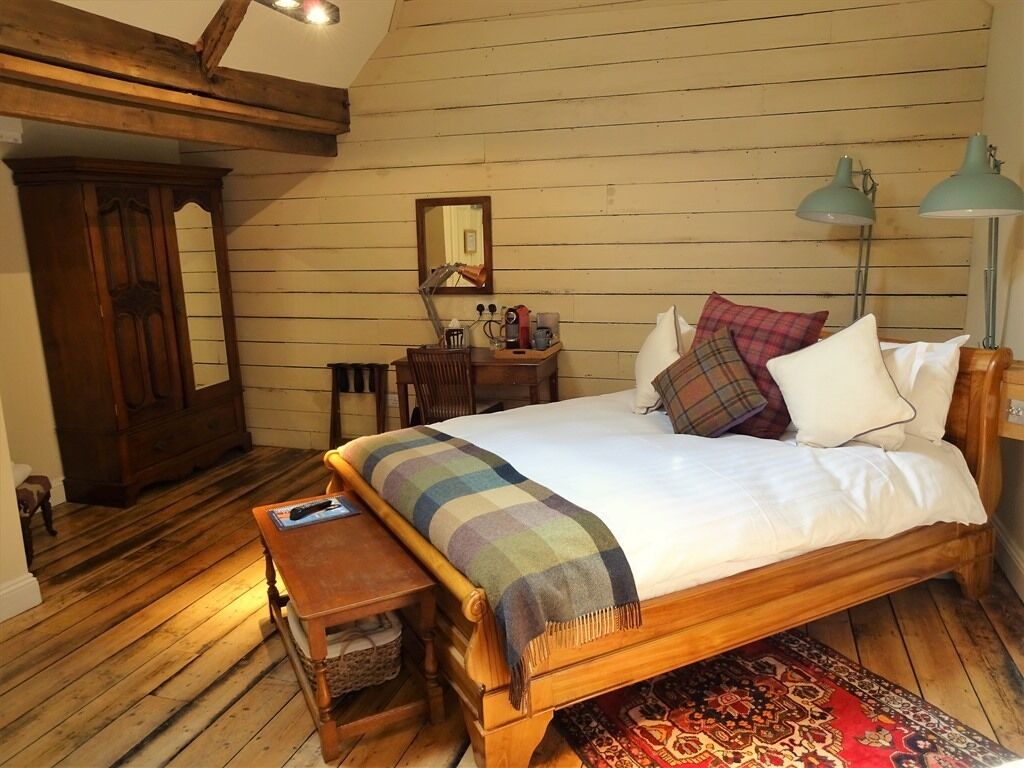 A cozy bedroom with a wooden bed, a nightstand, a dresser, and a mirror.