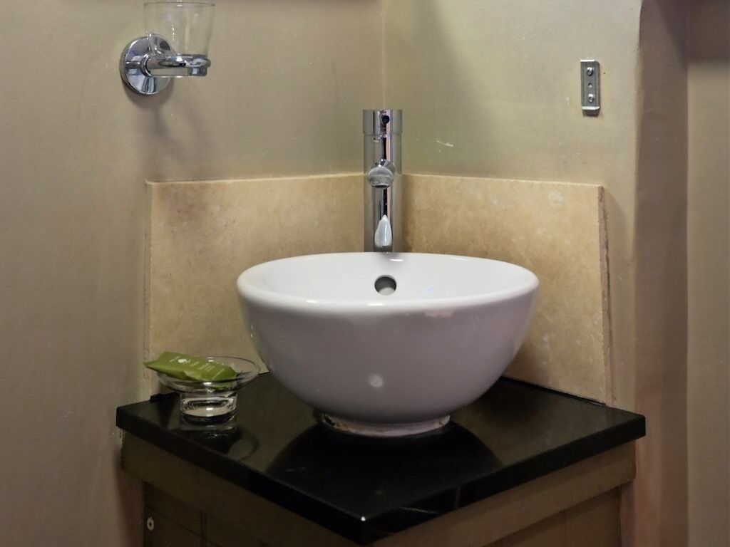 A bathroom with a white sink, a faucet, and a glass bowl on the countertop.