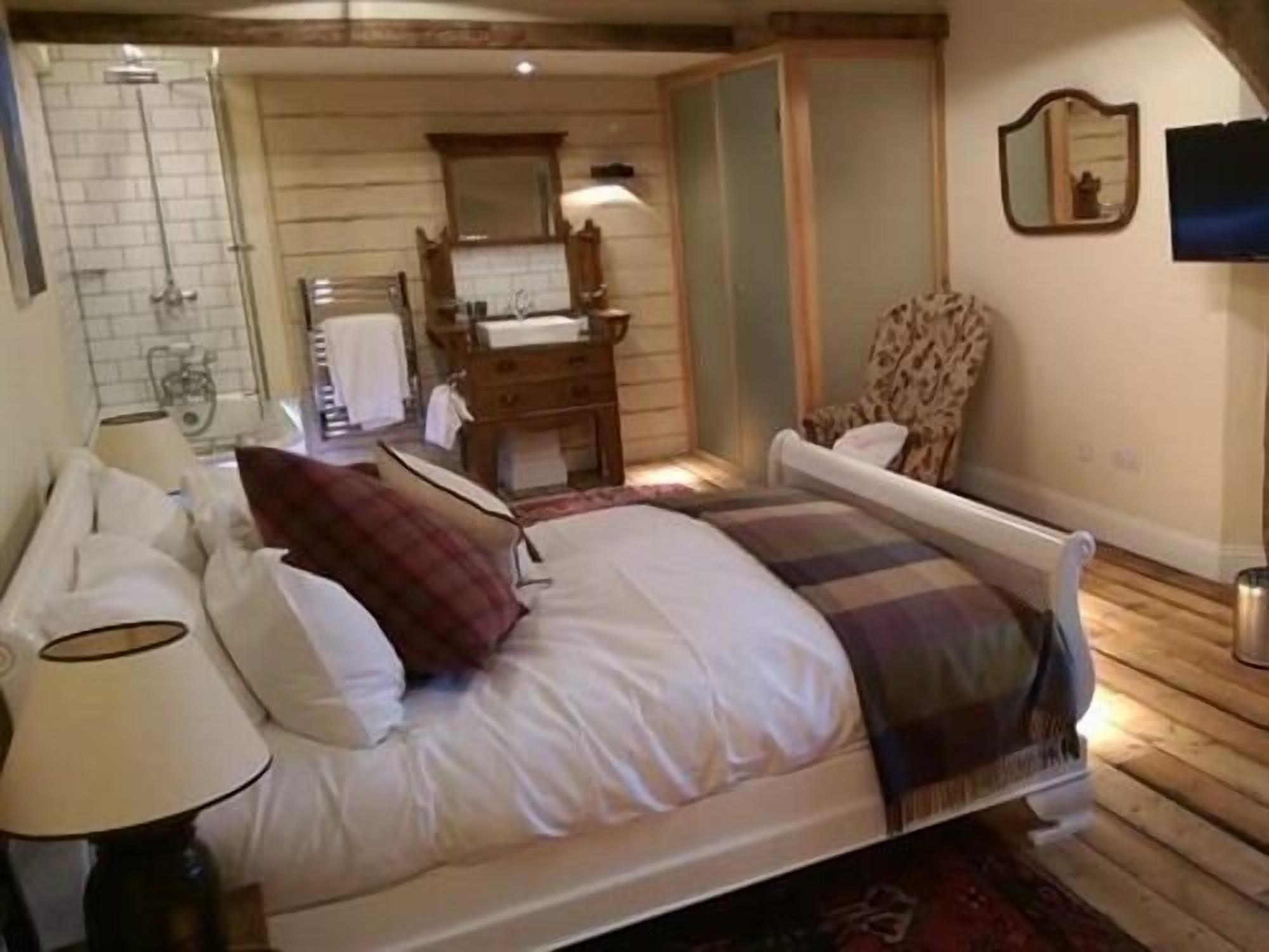 A bedroom with a bed, a nightstand, a lamp, a dresser, and a mirror.