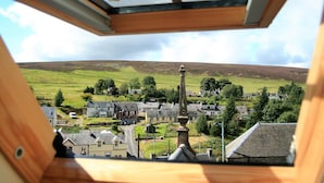 A view from a window overlooking a village with houses, a church, and a hill in the distance. - The Hopetoun Arms Hotel (Biggar)