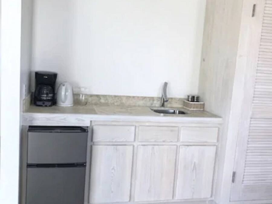 Eine kleine Küche mit Kühlschrank, Kaffeemaschine und Spüle.