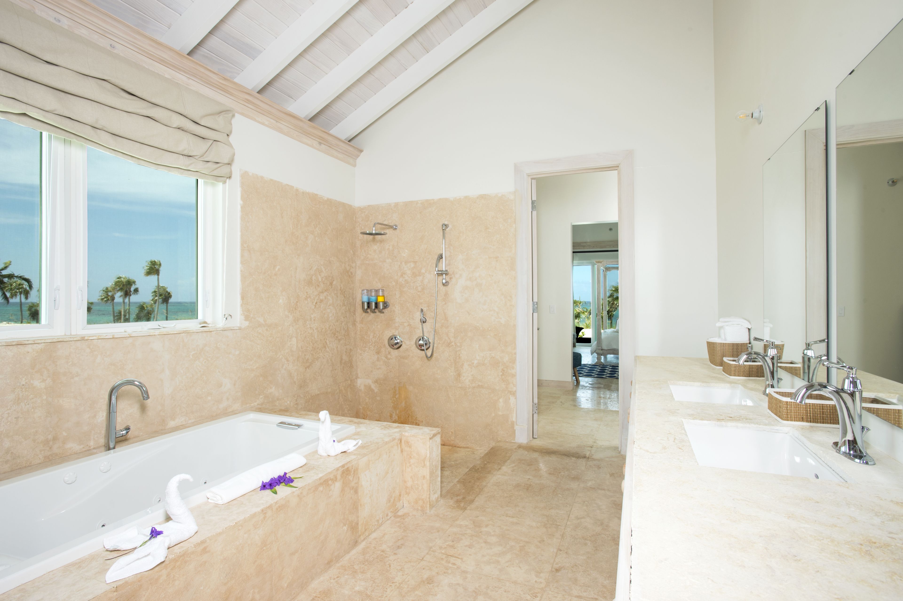 A modern bathroom with a large bathtub, two showers, and a vanity with three sinks.