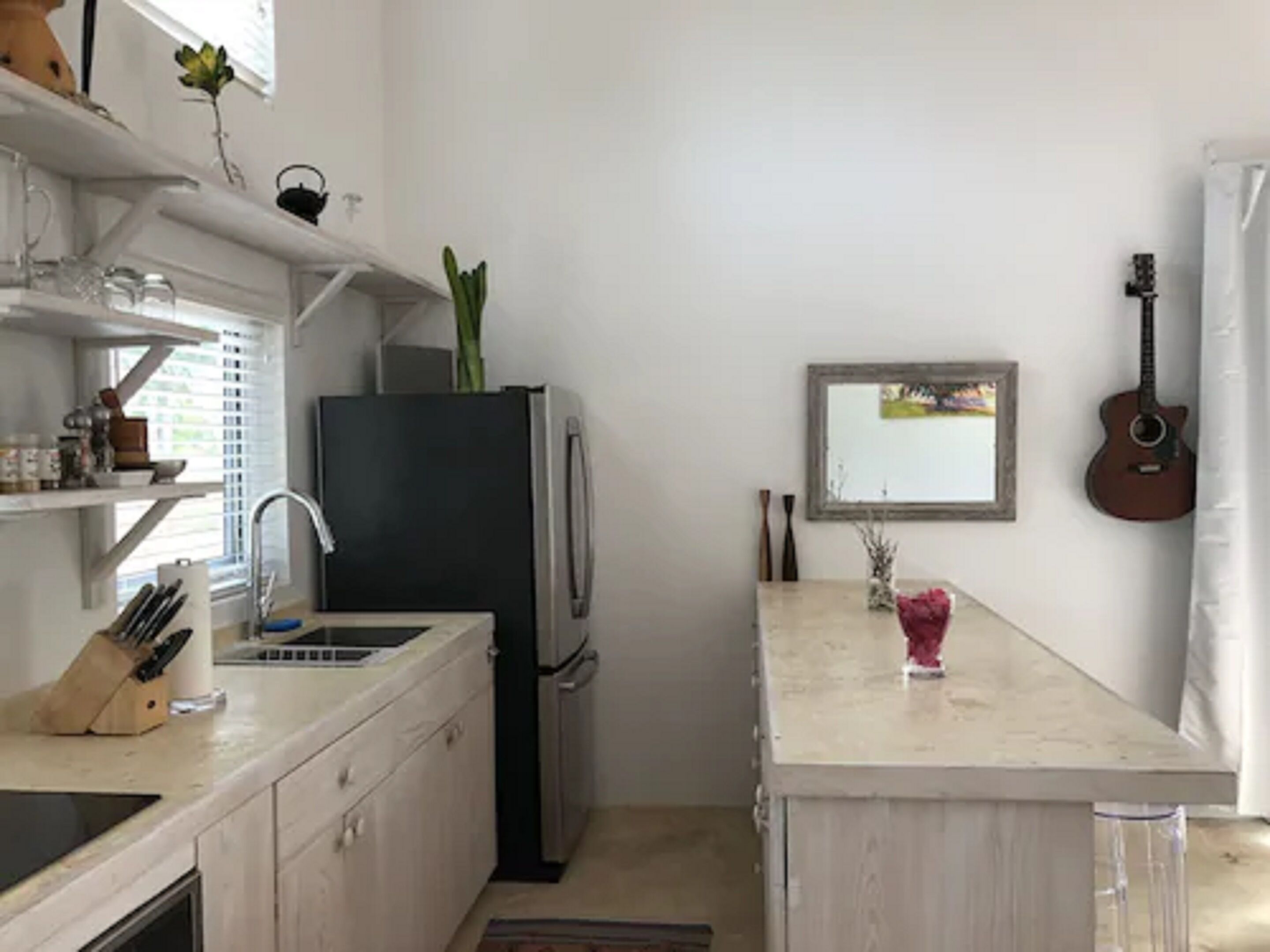 A kitchen with a refrigerator, sink, and a small island with a vase.