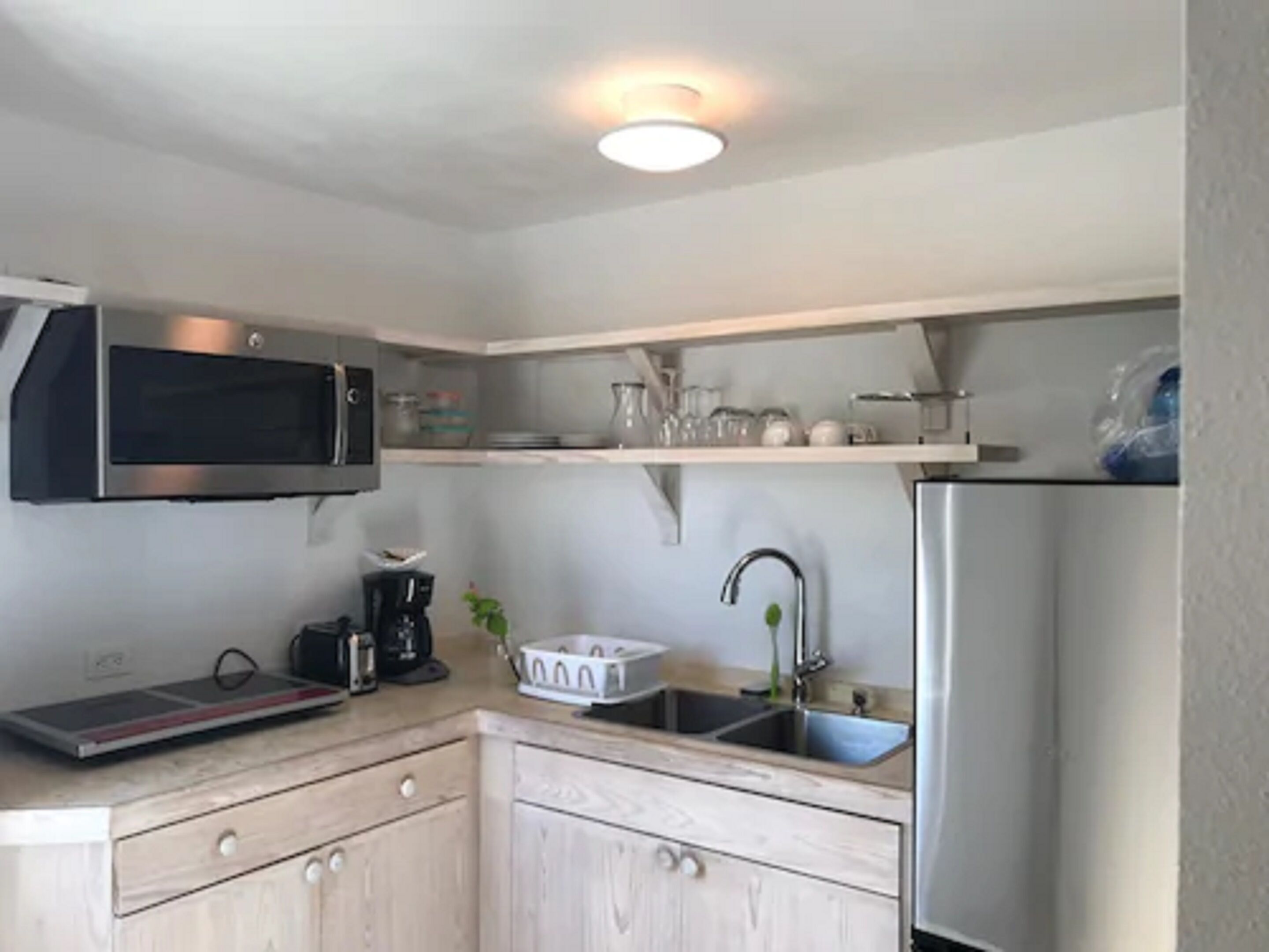 Eine kleine Küche mit Mikrowelle, Kaffeemaschine und Kühlschrank.