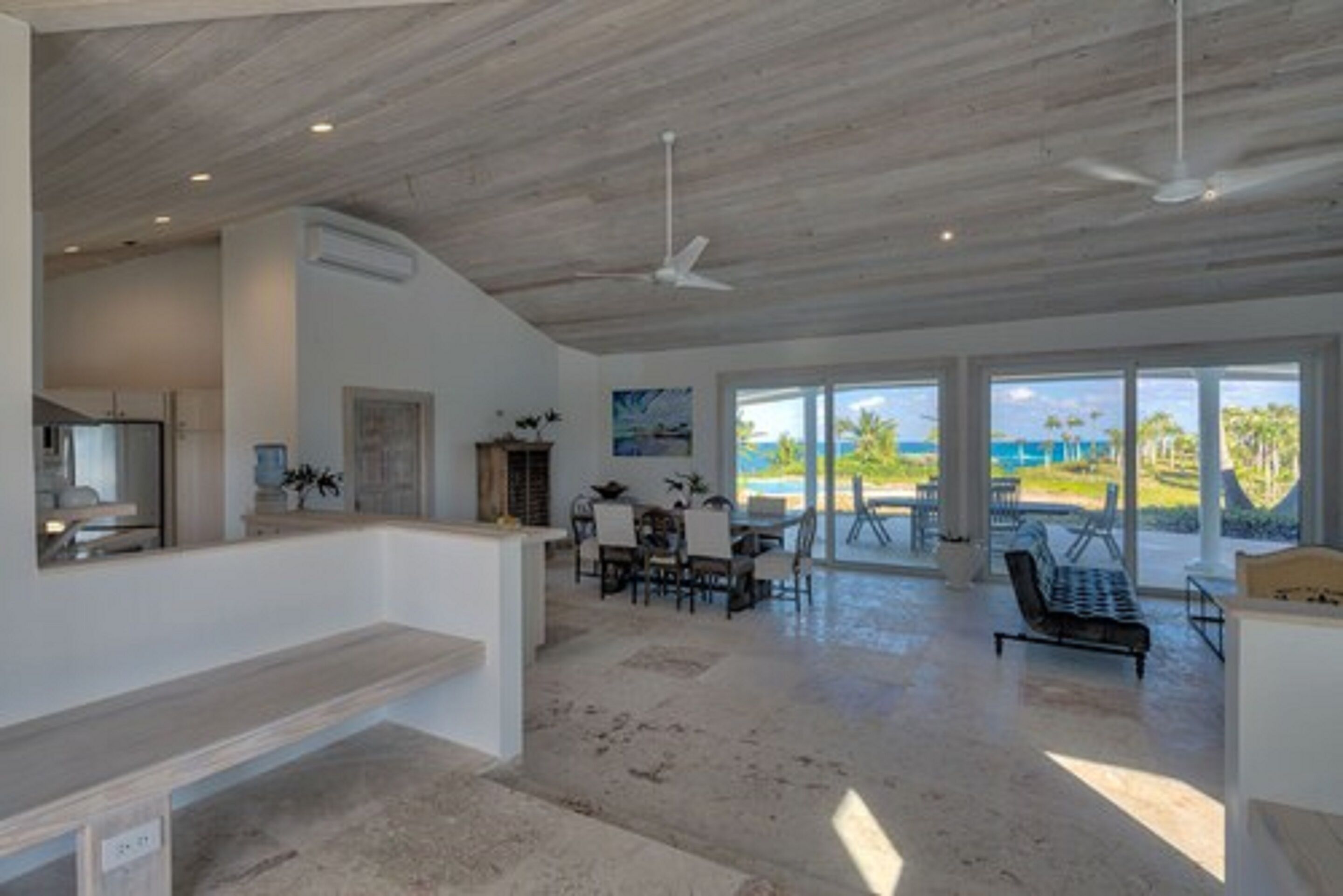 A spacious living area with a high ceiling, large windows, and a view of the outdoors.