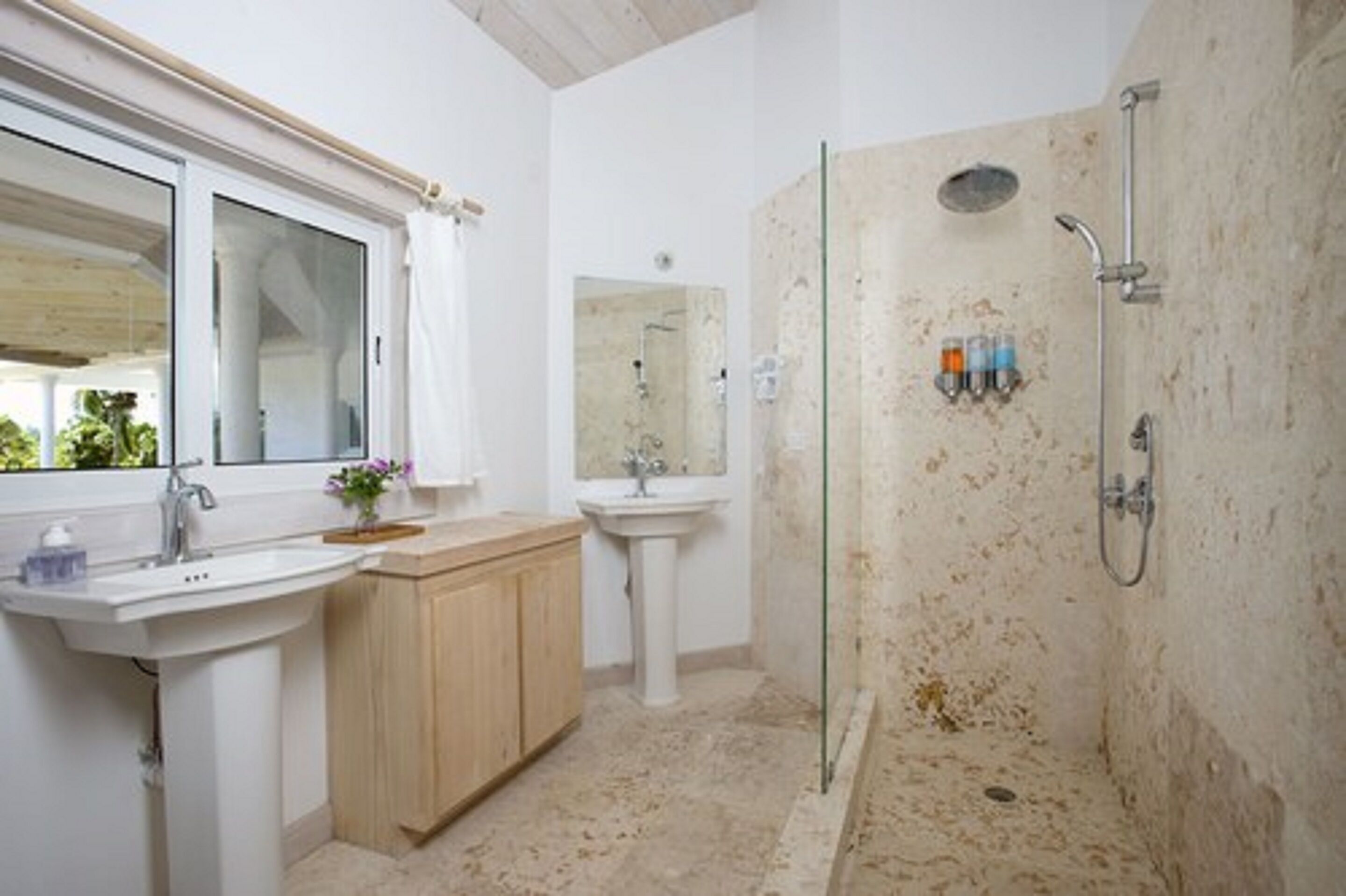 Un baño con ducha de vidrio, un lavabo y un espejo.
