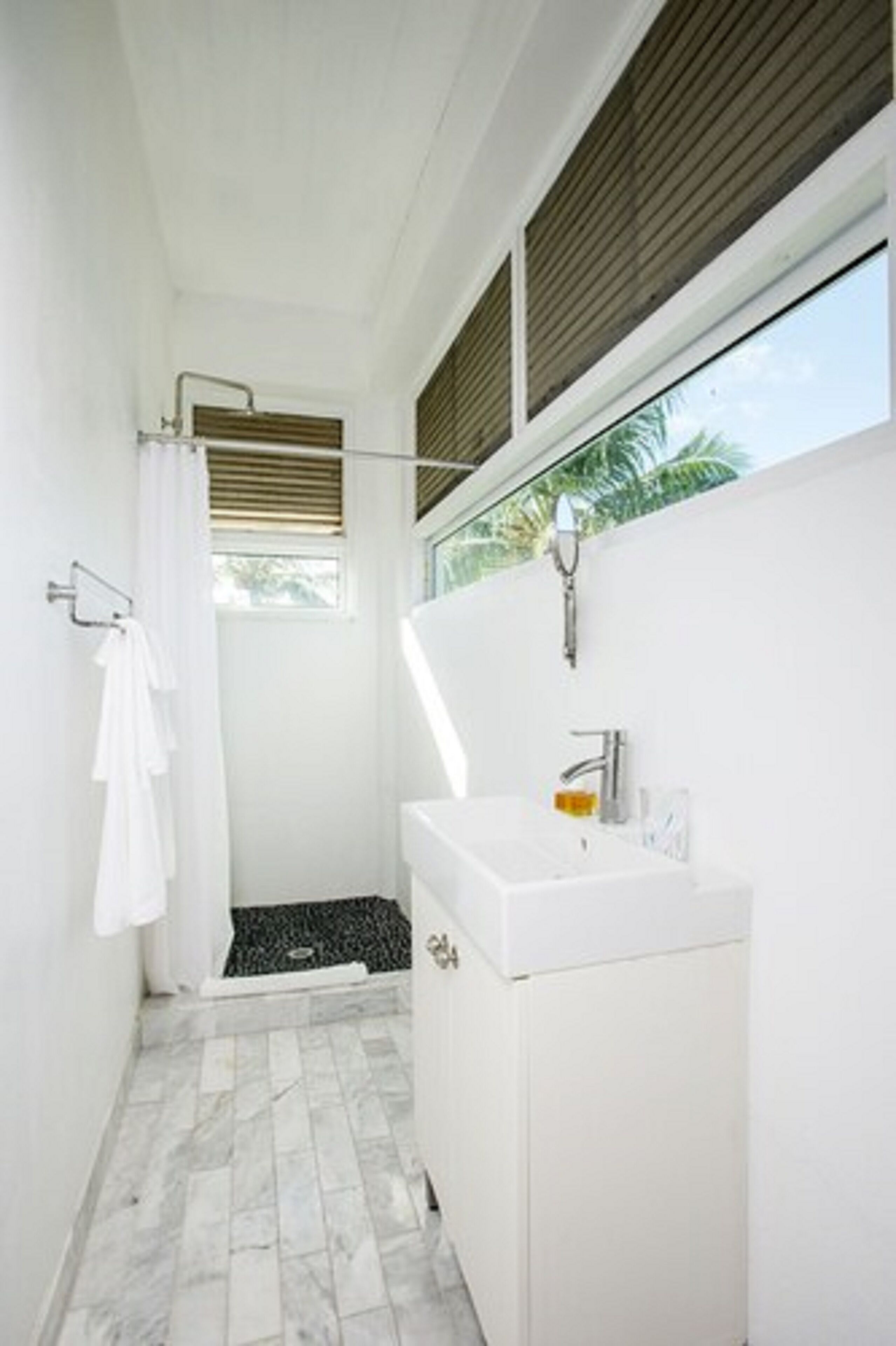 A bathroom with a shower, a sink, and a window.