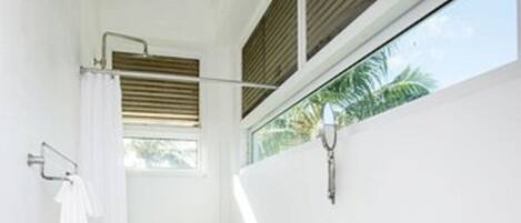 A bathroom with a shower, a sink, and a window.