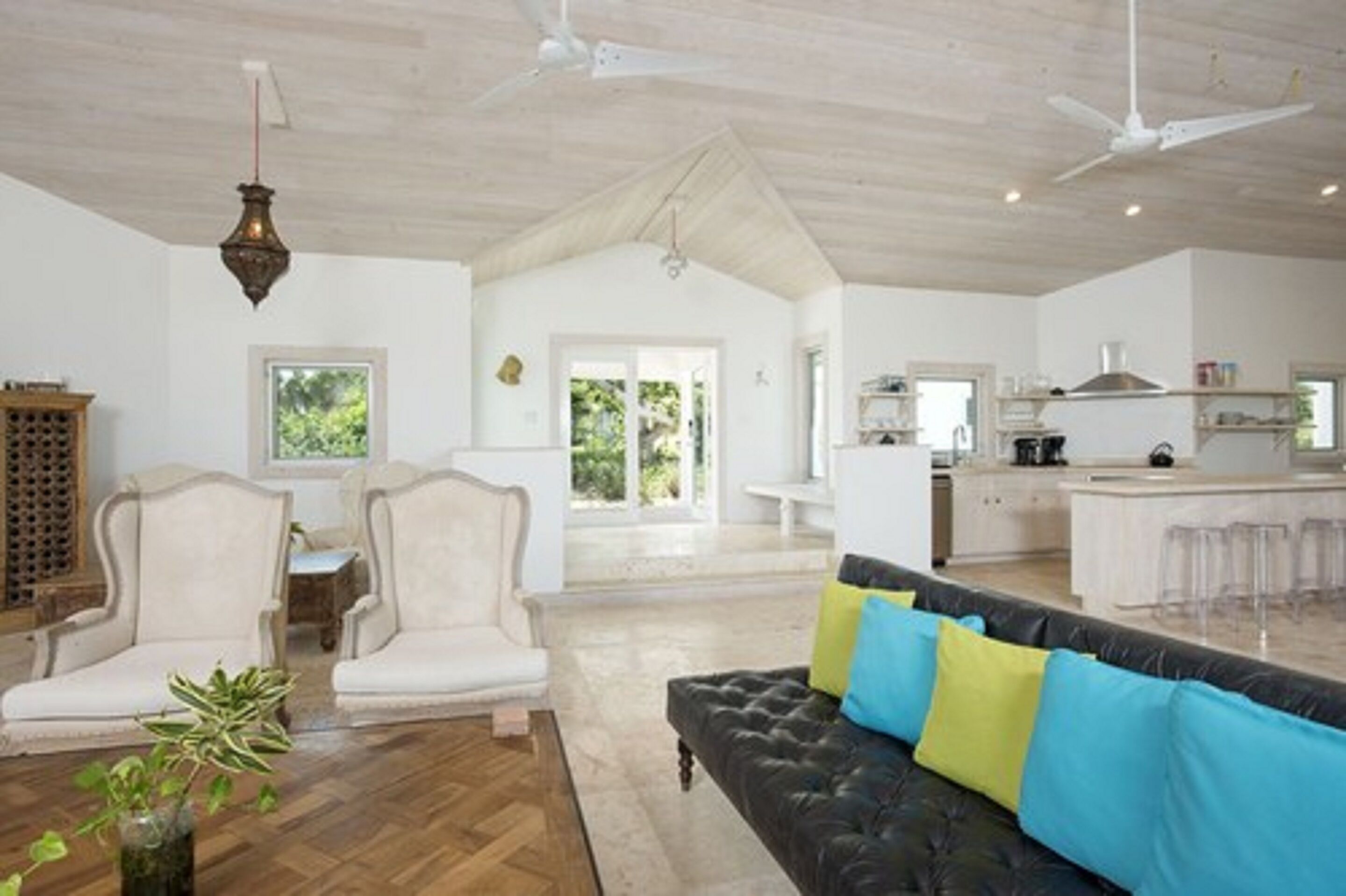 A spacious living area with a sofa, chairs, and a dining table. A kitchen is visible in the background with a bar area.