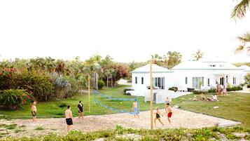 Guests can enjoy a game of beach volleyball in a tropical setting surrounded by lush greenery and palm trees.