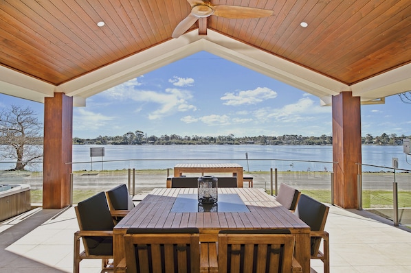 Una terraza de madera al aire libre con una mesa y sillas, con vista a un lago.