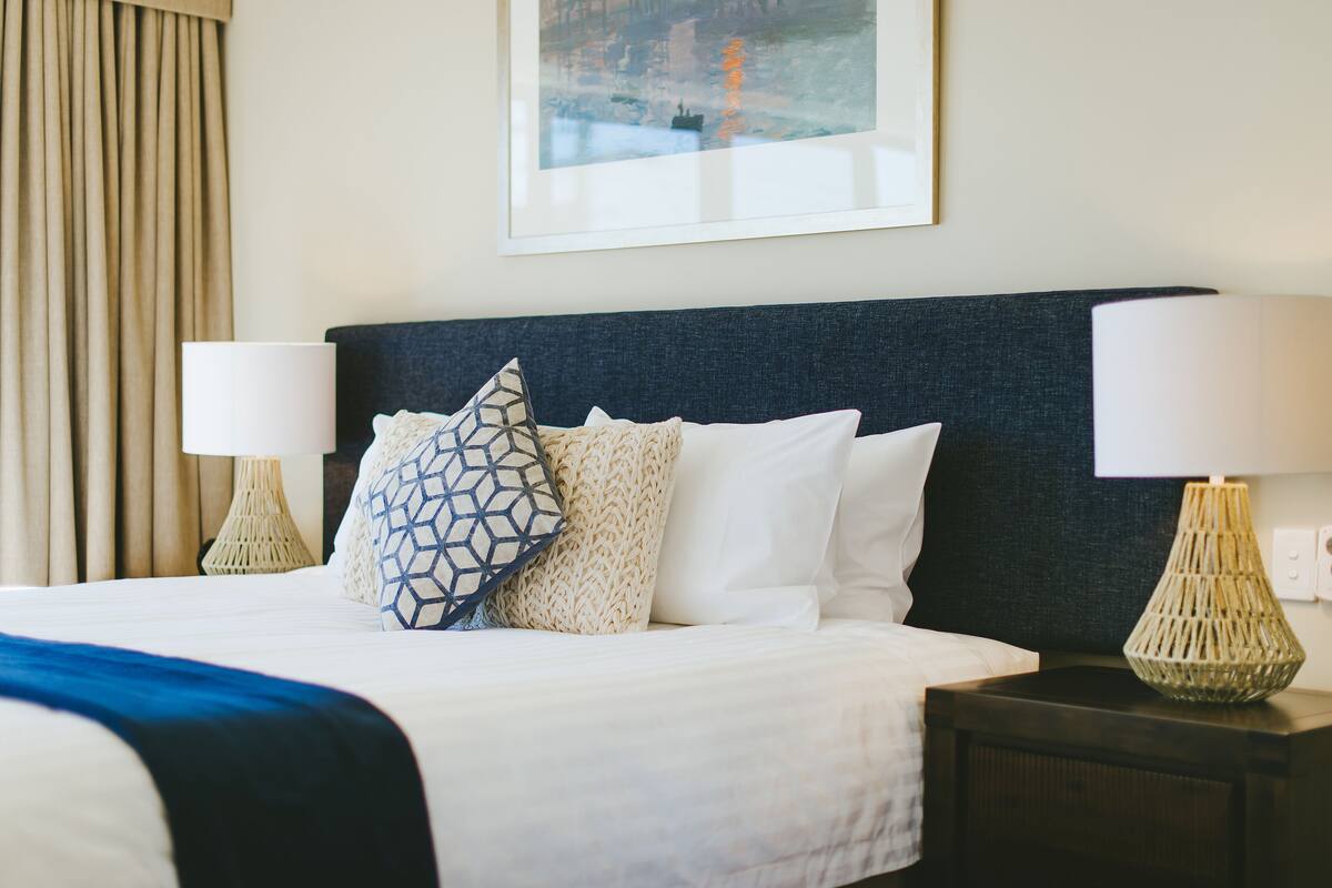 Habitación de hotel con una cama grande, dos lámparas de noche y un cuadro en la pared.