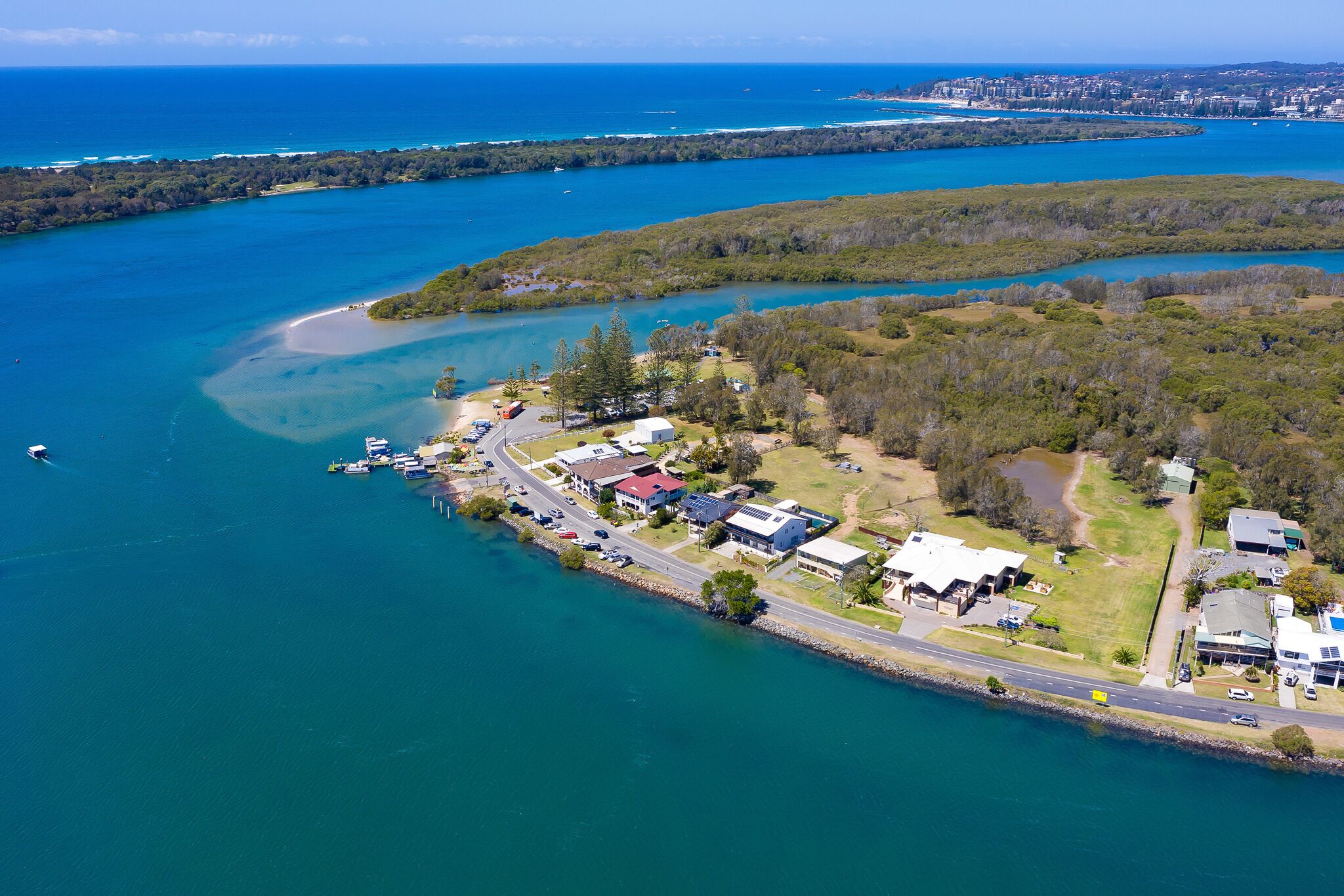 An aerial view of a coastal area with a marina, houses, and a road.