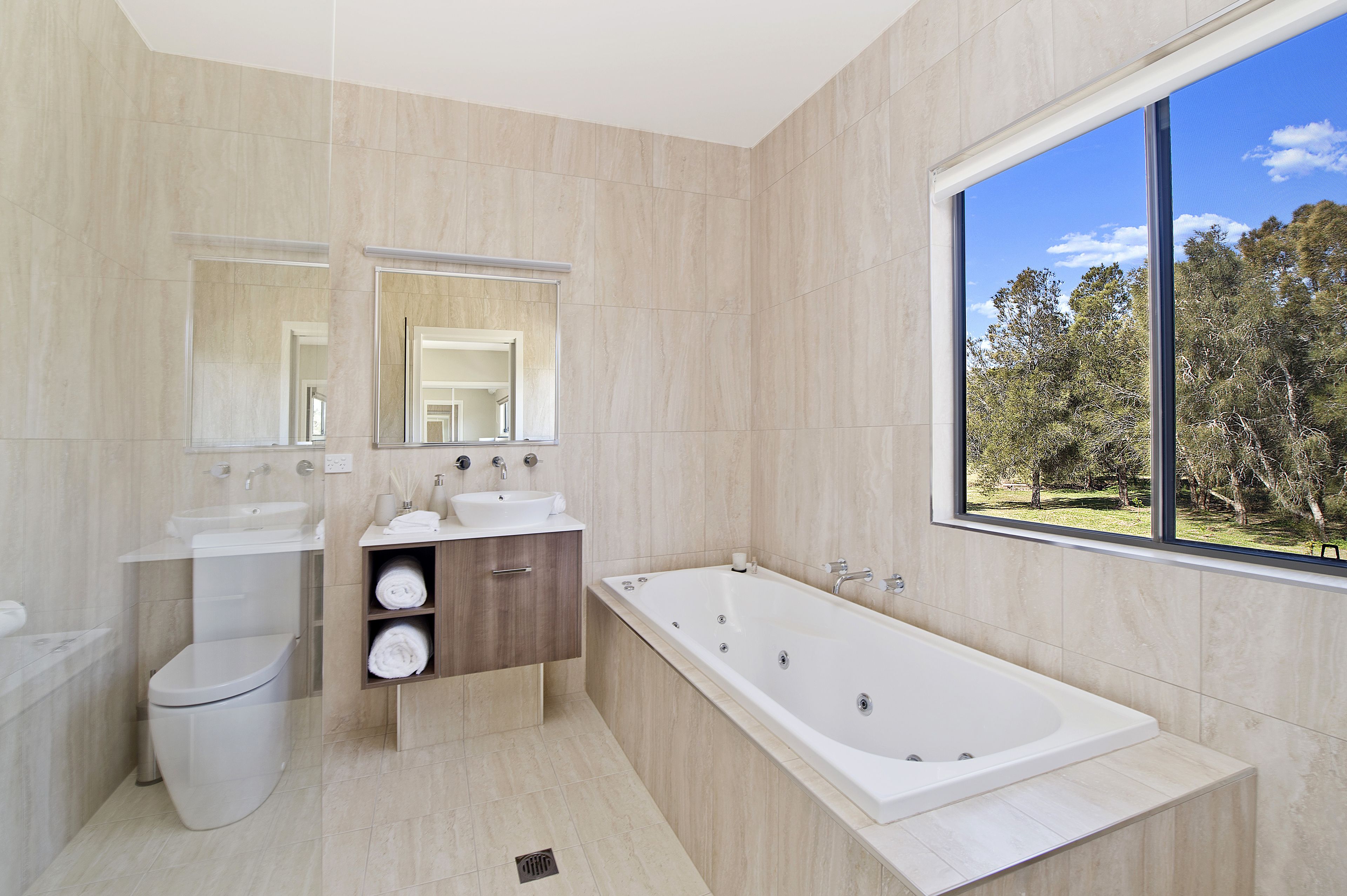 Une salle de bain moderne avec une grande baignoire, des toilettes et un meuble-lavabo avec un miroir.